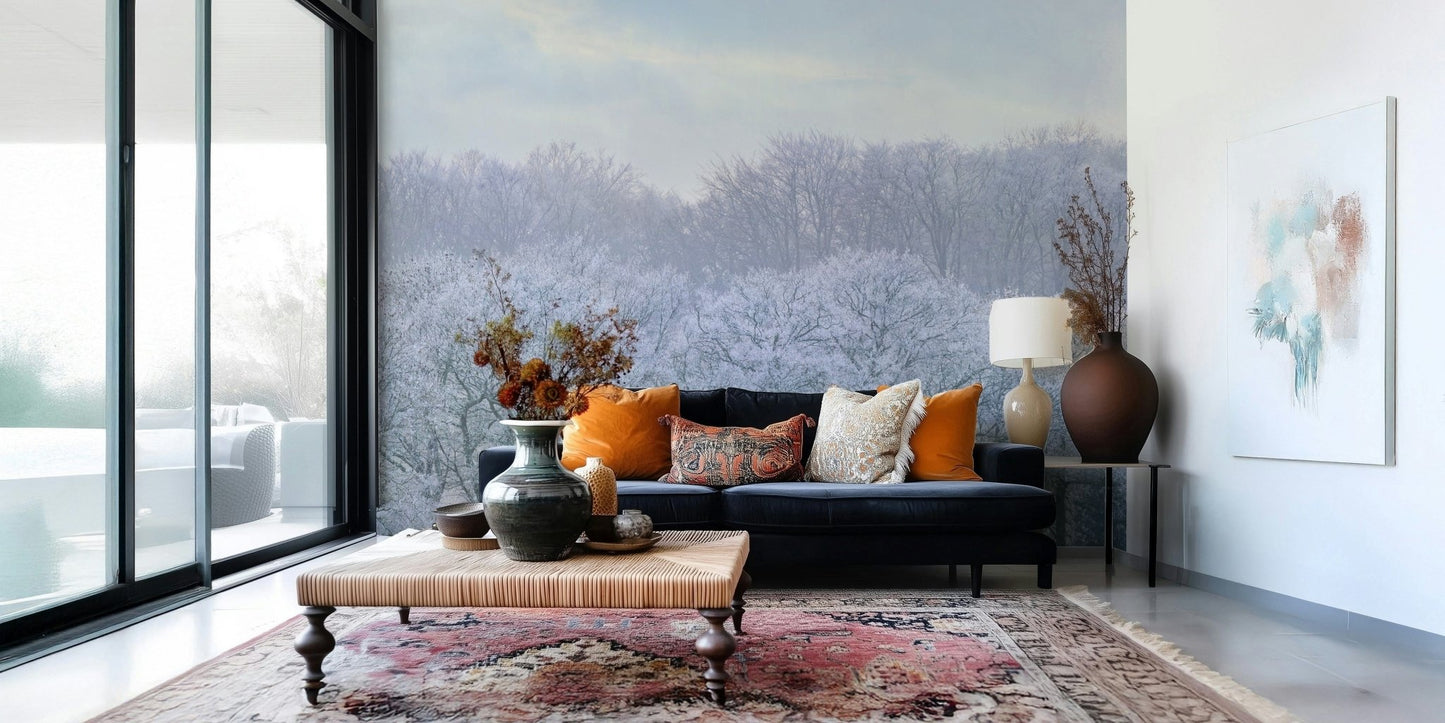Winter's Whispers wallpaper mural of icy winter woodland behind a navy velvet sofa with orange cushions in a living room