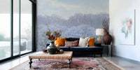 Winter's Whispers wallpaper mural of icy winter woodland behind a navy velvet sofa with orange cushions in a living room