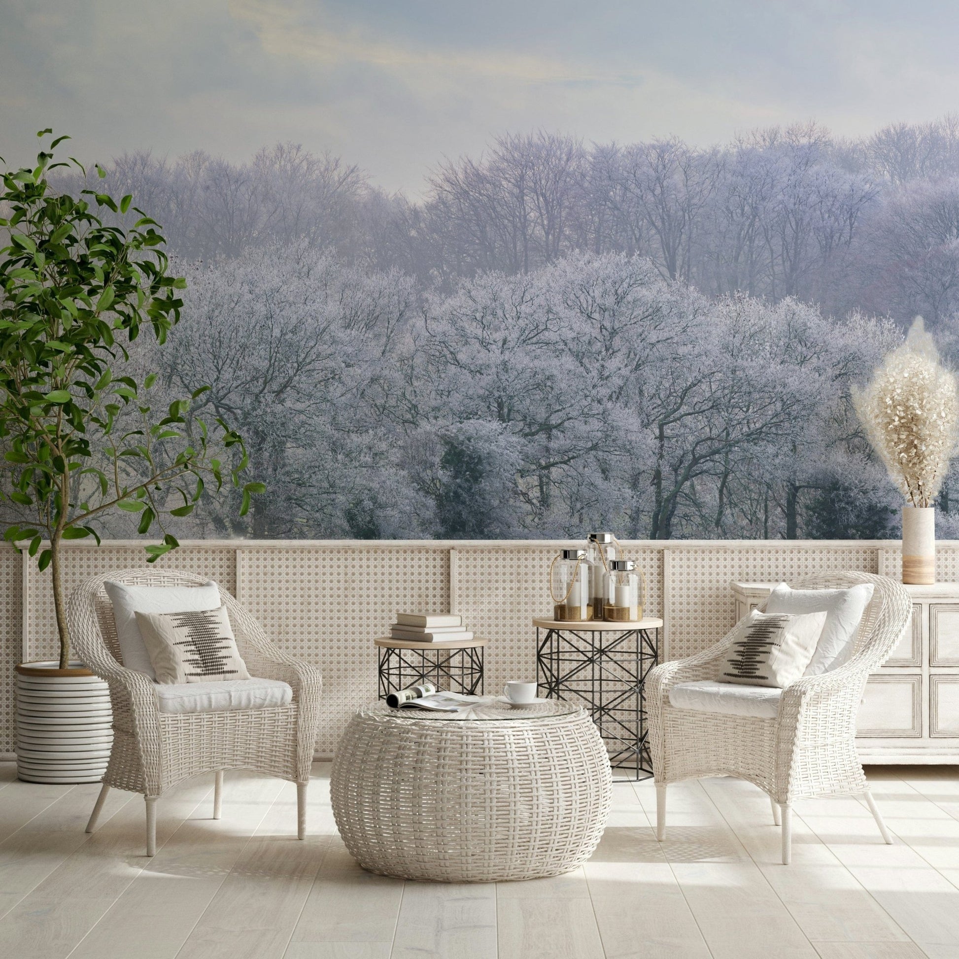 Winter's Whispers wallpaper mural of a frosty forest behind two white wicker armchairs on a cosy patio