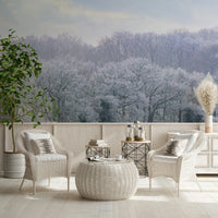 Winter's Whispers wallpaper mural of a frosty forest behind two white wicker armchairs on a cosy patio