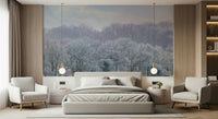 Winter's Whispers wallpaper mural of a frosted woodland under a pale sky behind a grey bed and two cream armchairs