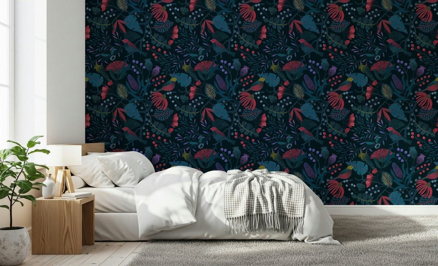 Wonderforest wallpaper with red and teal flowers behind a white bed and wood nightstand in a bedroom