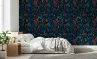 Wonderforest wallpaper with red and teal flowers behind a white bed and wood nightstand in a bedroom