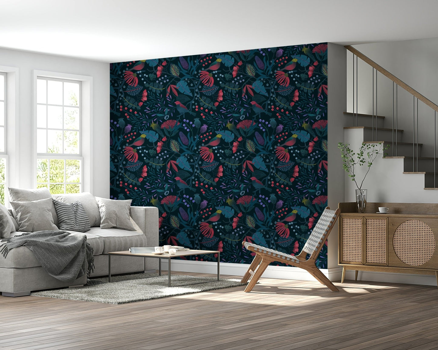 Wonderforest wallpaper in red and teal blooms behind a grey sofa and rattan sideboard in a bright living room