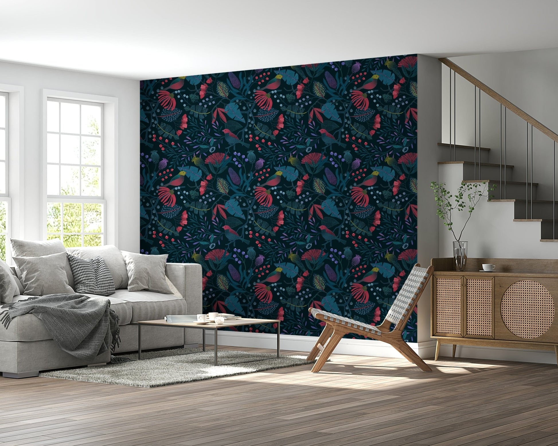 Wonderforest wallpaper in red and teal blooms behind a grey sofa and rattan sideboard in a bright living room