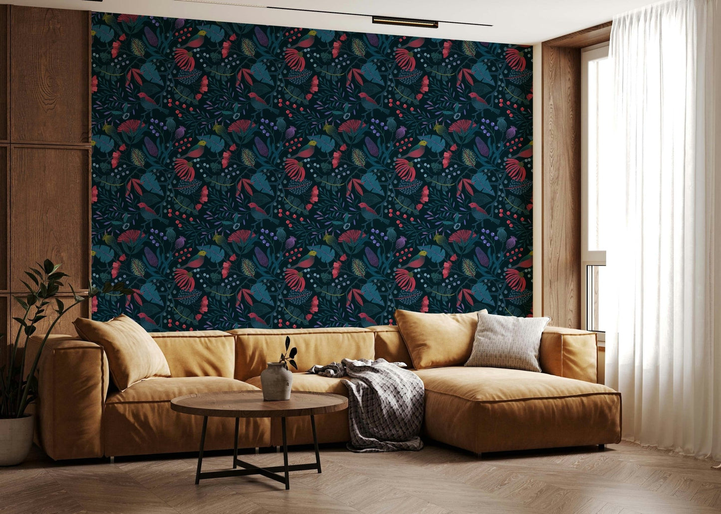 Wonderforest wallpaper of dark blooms and birds behind a mustard leather sectional sofa in a living room