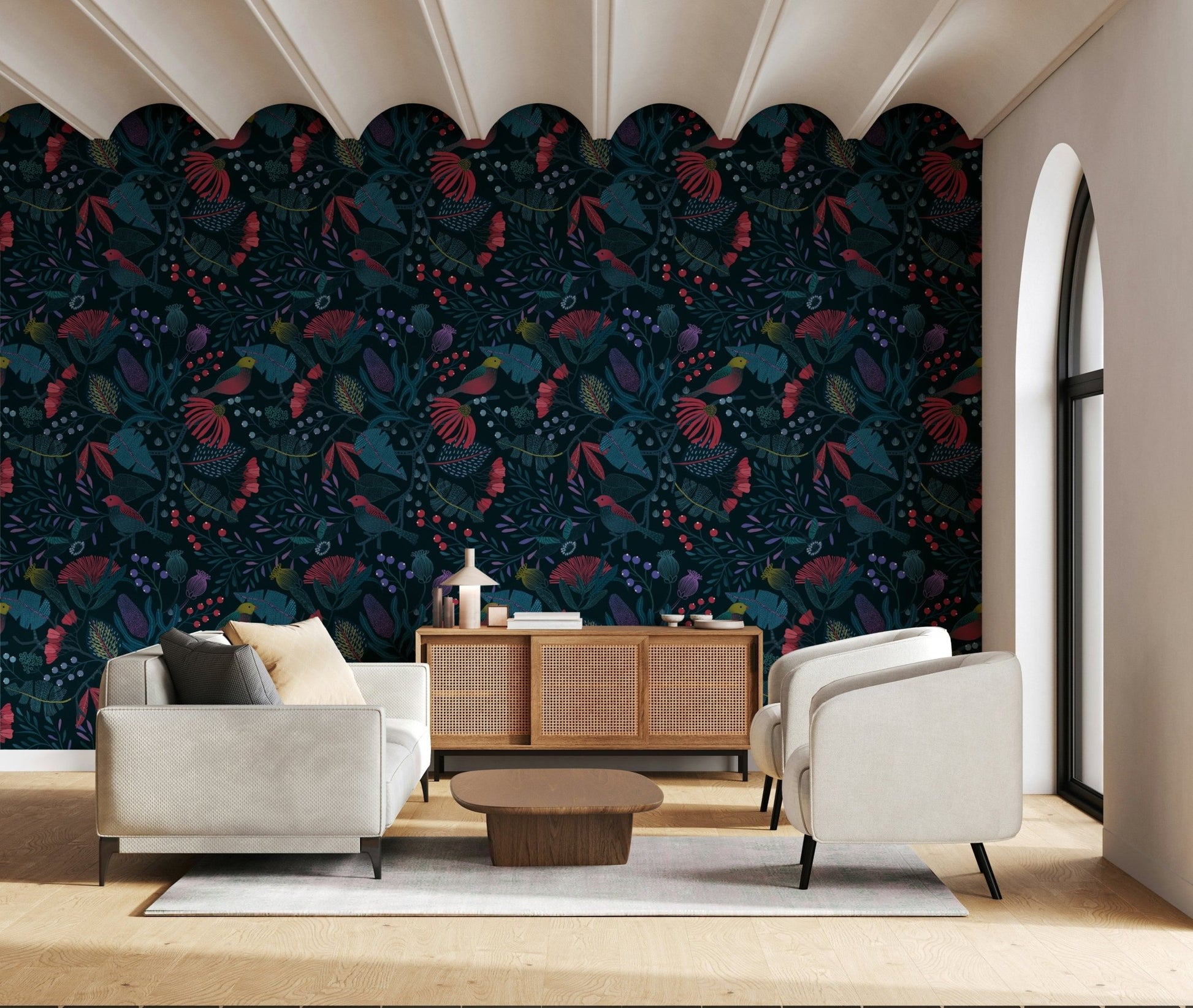 Wonderforest wallpaper with dark florals behind two cream armchairs and a rattan sideboard in a living room