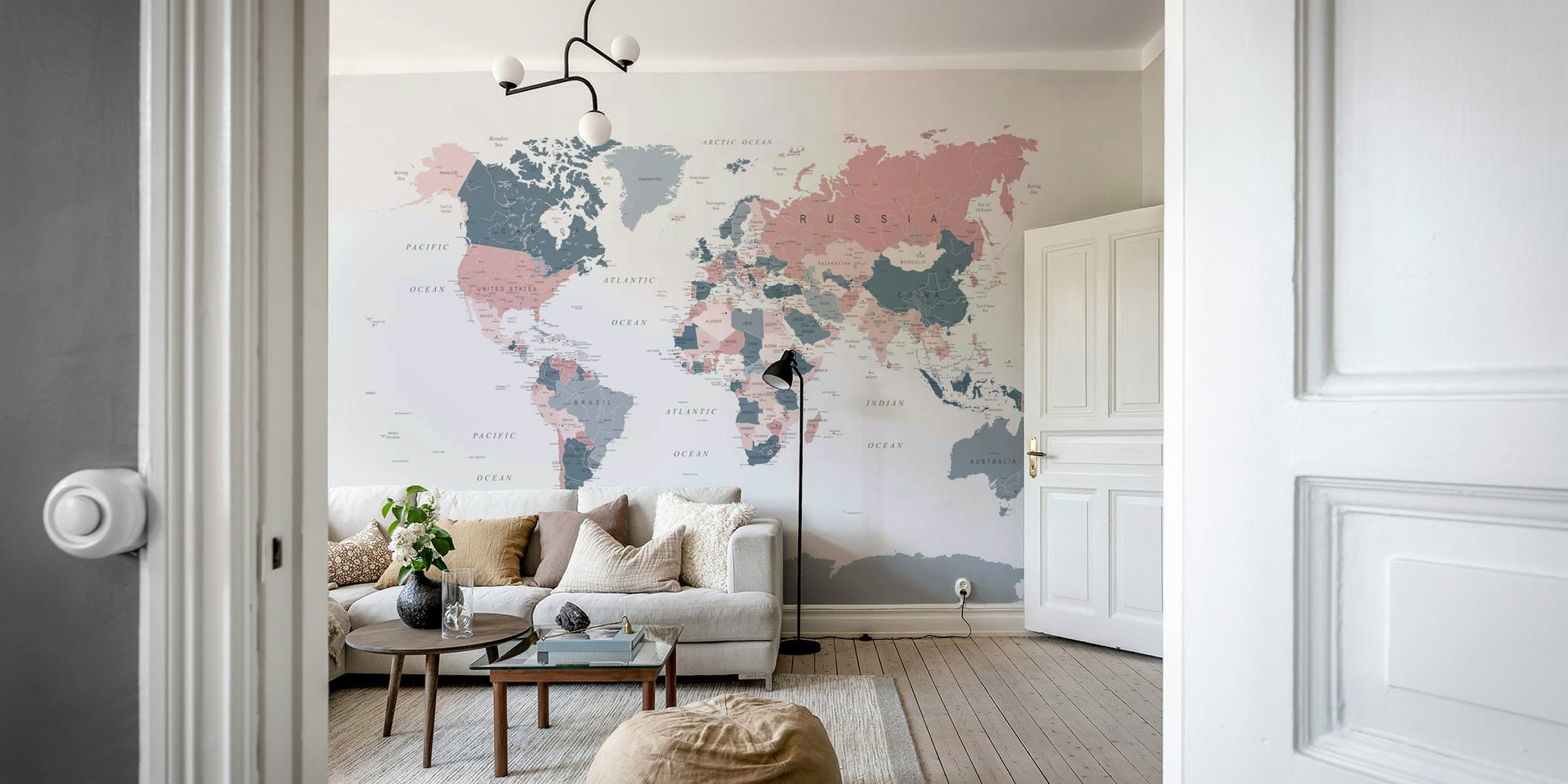 World Map Blush Pink and Indigo wallpaper mural above a white sofa and round coffee table in a living room