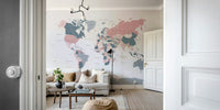 World Map Blush Pink and Indigo wallpaper mural above a white sofa and round coffee table in a living room