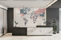 World Map Blush Pink and Indigo wallpaper mural behind a dark marble reception desk and plants in an office
