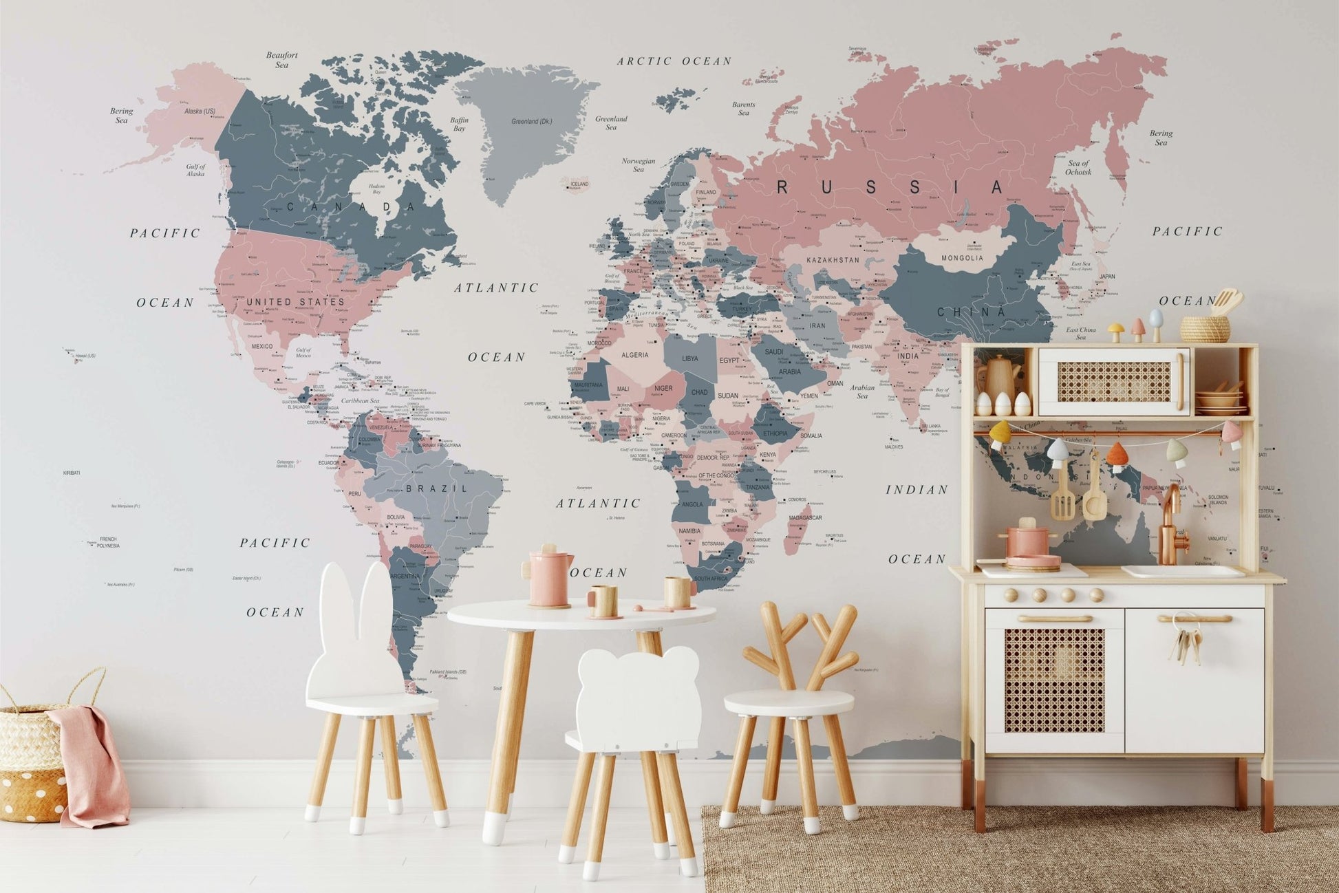 World Map Blush Pink and Indigo wallpaper mural in a kids room with animal-shaped chairs and a toy kitchen