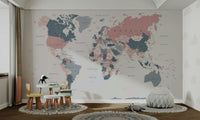 World Map Blush Pink and Indigo wallpaper mural in a playroom with a child table, stools and white beanbag