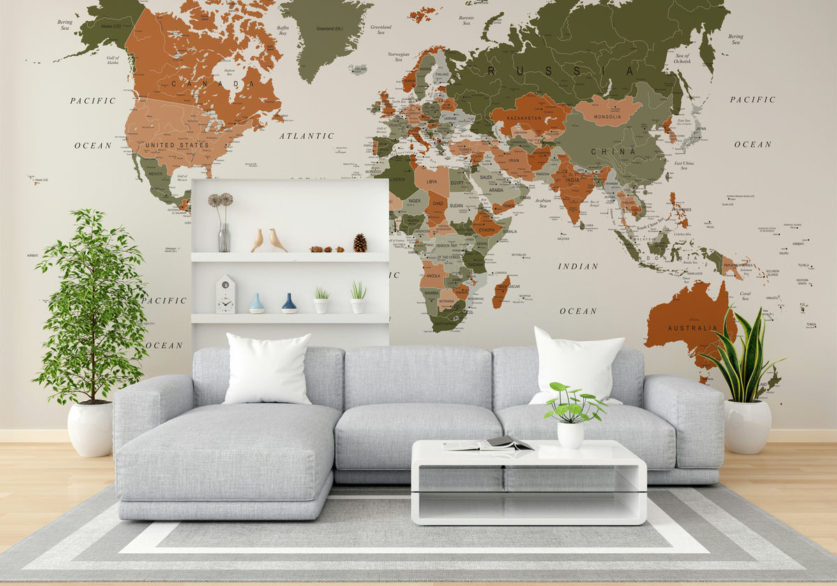 World Map Olive Green wallpaper mural in olive and terracotta behind a grey sectional sofa and white floating shelves in a living room